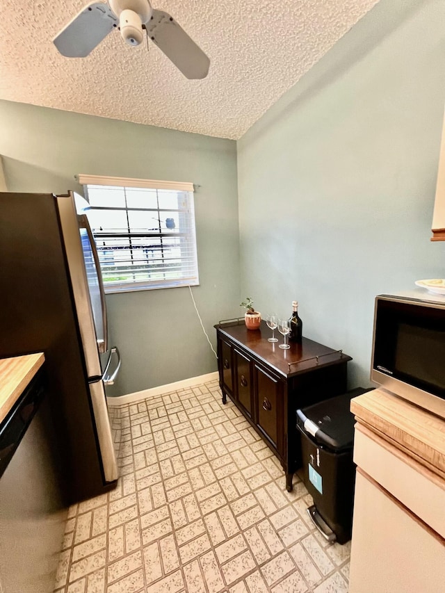 kitchen featuring ceiling fan, stainless steel appliances, wooden counters, a textured ceiling, and dark brown cabinets