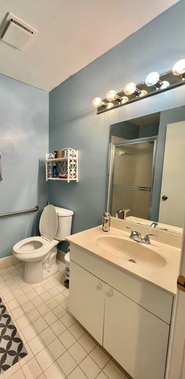 bathroom with tile patterned flooring, vanity, toilet, and an enclosed shower