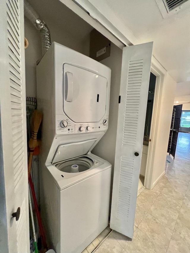 laundry room featuring light tile patterned floors and stacked washer / drying machine