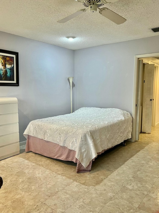 bedroom with ceiling fan and a textured ceiling