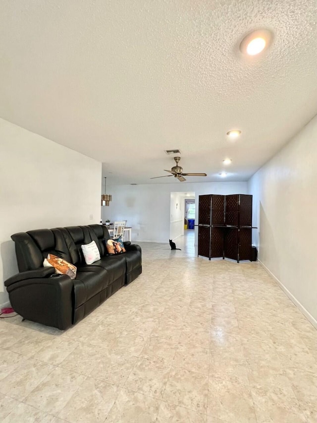 living room featuring ceiling fan and a textured ceiling