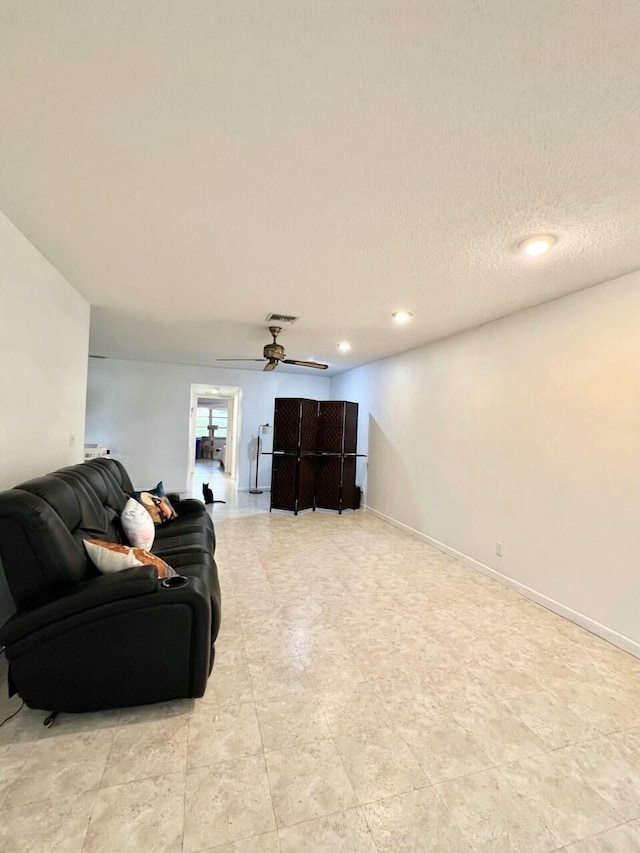 living room with ceiling fan and a textured ceiling