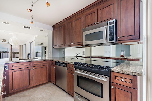 kitchen with sink, stainless steel appliances, light stone counters, kitchen peninsula, and a chandelier