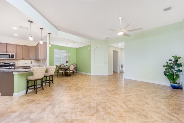 kitchen featuring stainless steel appliances, tasteful backsplash, pendant lighting, a kitchen bar, and light tile patterned floors