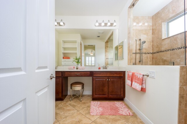 bathroom with a tile shower, vanity, and tile patterned floors