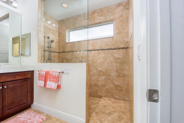 bathroom featuring a tile shower, tile patterned floors, and vanity