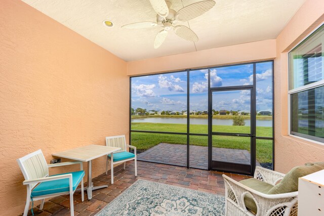 sunroom / solarium with ceiling fan and a water view