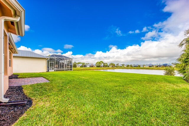 view of yard featuring glass enclosure and a water view