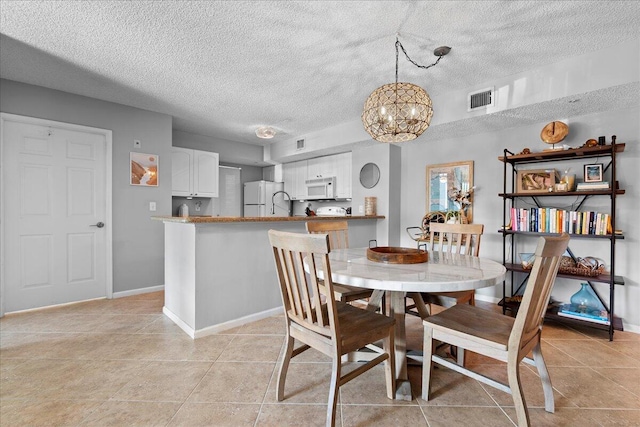 tiled dining room with a textured ceiling and a notable chandelier