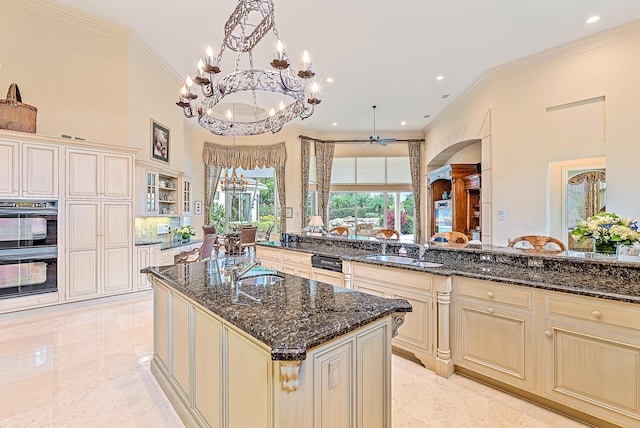 kitchen with dark stone countertops, an island with sink, and pendant lighting