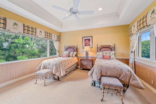 carpeted bedroom featuring ceiling fan, wood walls, a raised ceiling, and ornamental molding