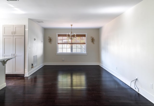 unfurnished dining area featuring dark hardwood / wood-style flooring and an inviting chandelier