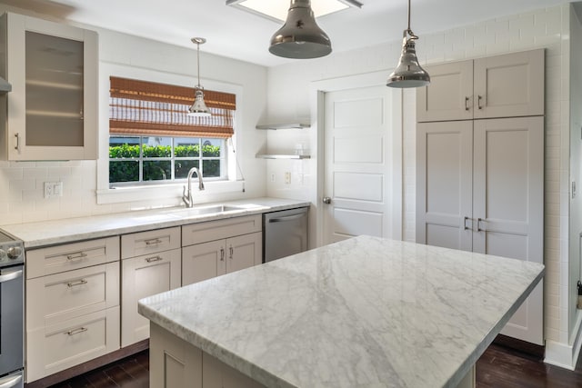 kitchen featuring sink, light stone countertops, tasteful backsplash, decorative light fixtures, and stainless steel appliances