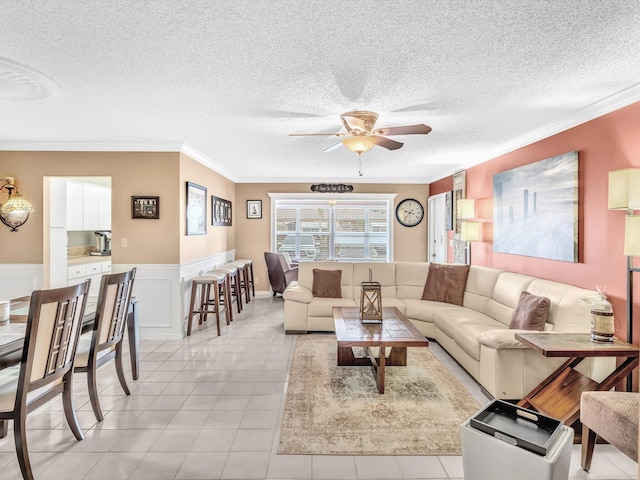 living room with crown molding, ceiling fan, light tile patterned flooring, and a textured ceiling