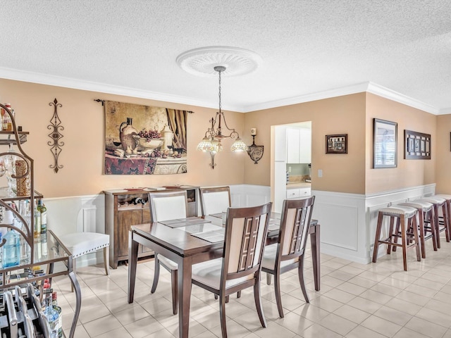 dining room featuring light tile patterned floors, a textured ceiling, and crown molding