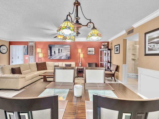 dining area featuring a chandelier, a textured ceiling, and ornamental molding