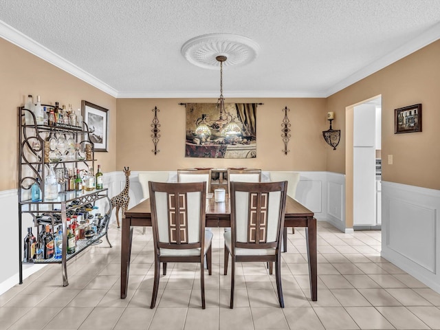 tiled dining space featuring ornamental molding and a textured ceiling