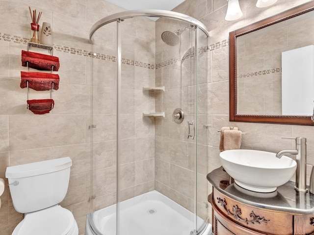 bathroom with sink, a shower with door, tile walls, and toilet