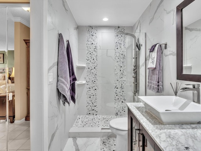 bathroom featuring a tile shower, vanity, and toilet