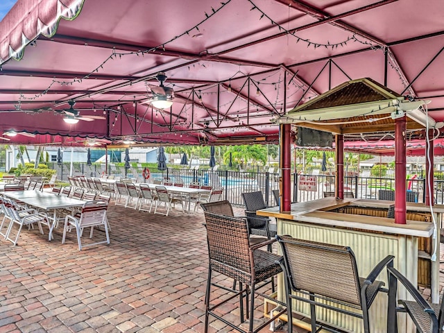 view of patio featuring ceiling fan and a bar