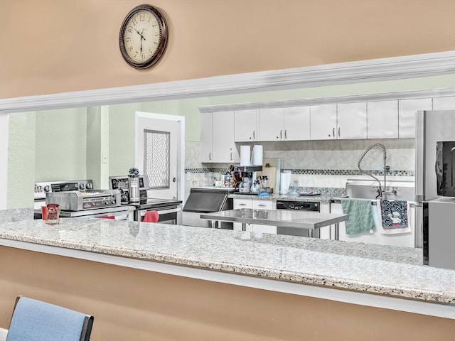 kitchen with backsplash, light stone countertops, and white cabinets