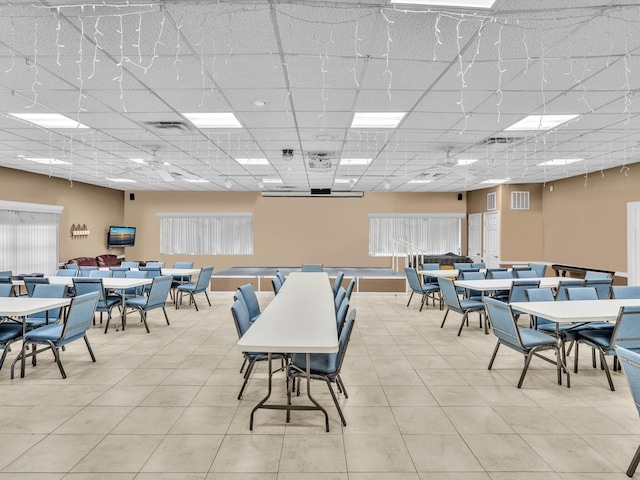 tiled dining space featuring a drop ceiling