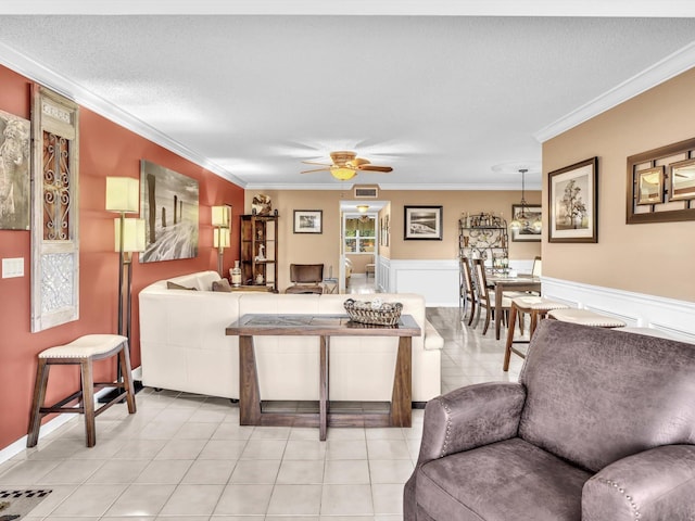 tiled living room with a textured ceiling, ceiling fan, and ornamental molding