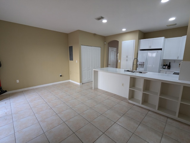 kitchen with white cabinetry, sink, white fridge with ice dispenser, electric panel, and light tile patterned floors