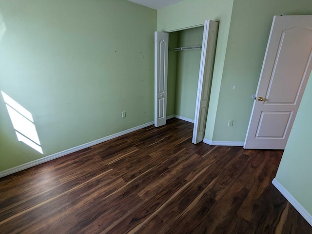 unfurnished bedroom with dark wood-type flooring and a closet