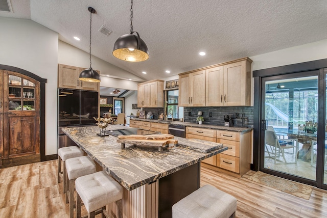 kitchen featuring light brown cabinets and vaulted ceiling