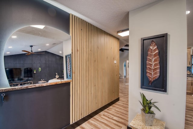 interior space with wood-type flooring, a textured ceiling, wooden walls, and lofted ceiling