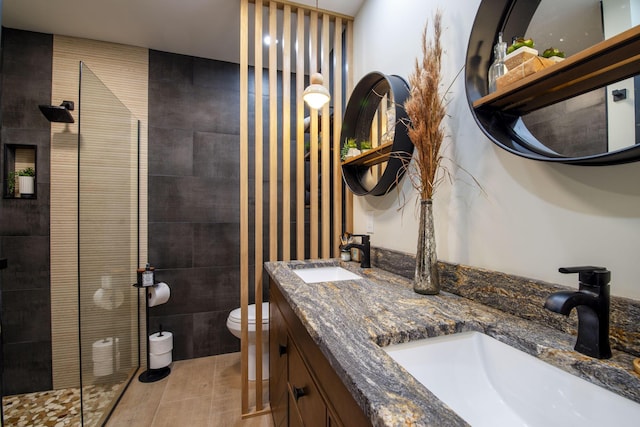 bathroom with tile patterned flooring, vanity, toilet, and tiled shower