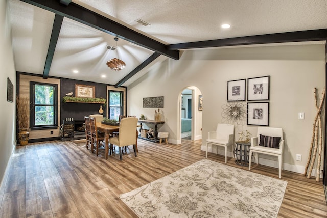 dining space with hardwood / wood-style floors, lofted ceiling with beams, and a textured ceiling