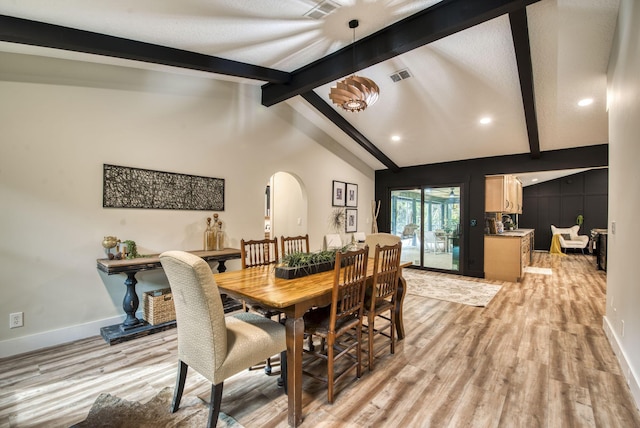 dining space featuring vaulted ceiling with beams and light hardwood / wood-style flooring