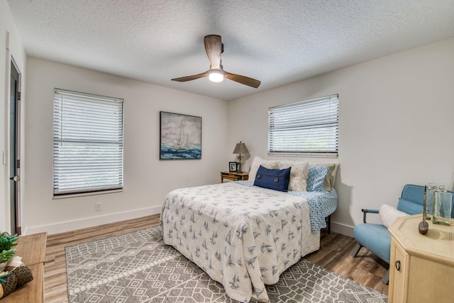 bedroom with hardwood / wood-style floors, ceiling fan, a textured ceiling, and multiple windows