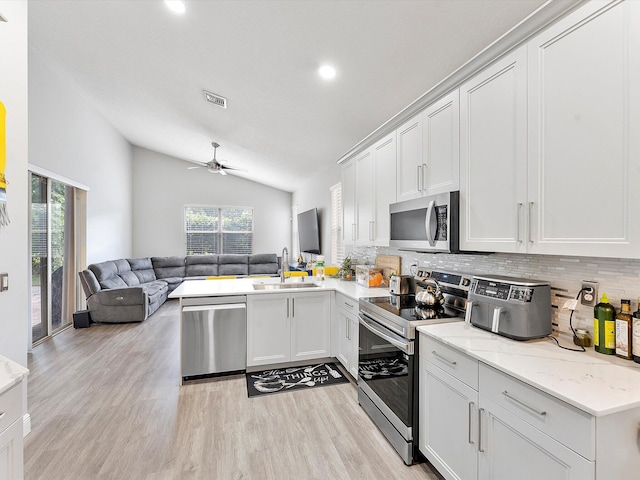 kitchen featuring backsplash, stainless steel appliances, sink, white cabinetry, and lofted ceiling