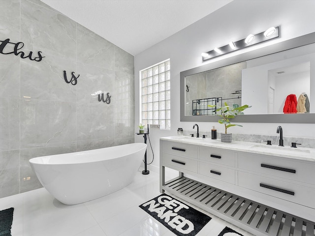 bathroom featuring tile patterned floors, vanity, vaulted ceiling, tile walls, and a tub