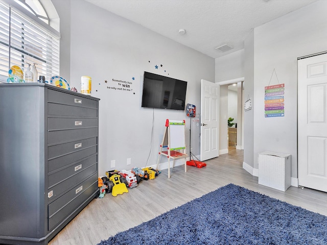 game room featuring a textured ceiling and light hardwood / wood-style flooring