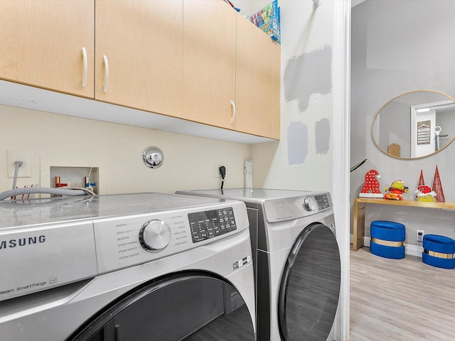 laundry area featuring cabinets, independent washer and dryer, and light wood-type flooring