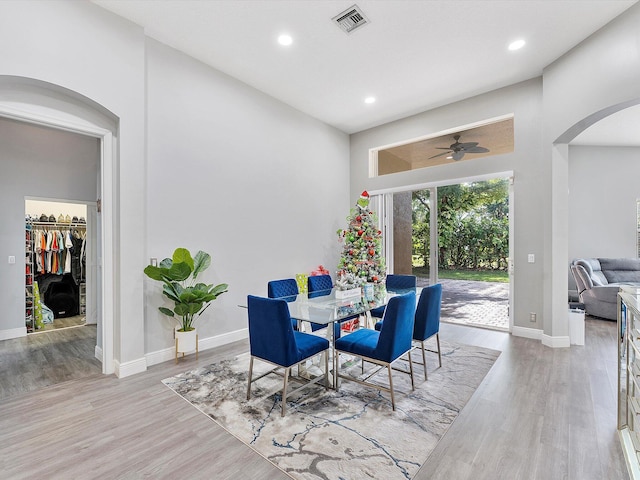 dining area with ceiling fan, light hardwood / wood-style floors, and a towering ceiling