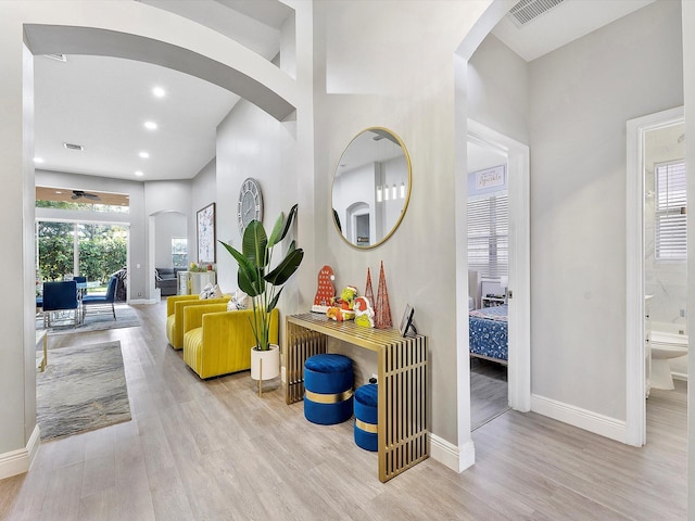 hallway featuring a towering ceiling and light hardwood / wood-style floors