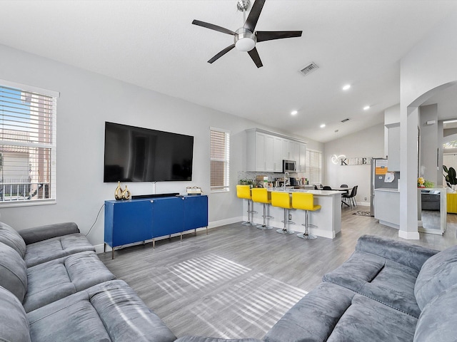 living room featuring light hardwood / wood-style floors, vaulted ceiling, and ceiling fan