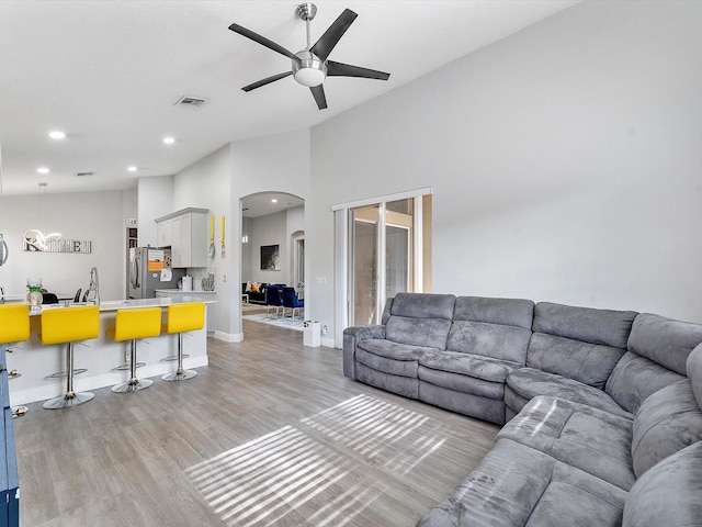 living room featuring a towering ceiling, light hardwood / wood-style floors, ceiling fan, and sink