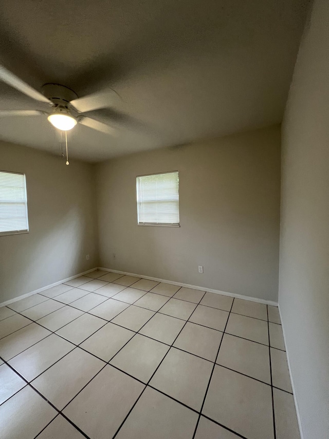 tiled empty room featuring a wealth of natural light and ceiling fan