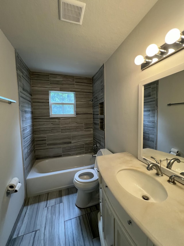 full bathroom featuring a textured ceiling, vanity, toilet, and tiled shower / bath