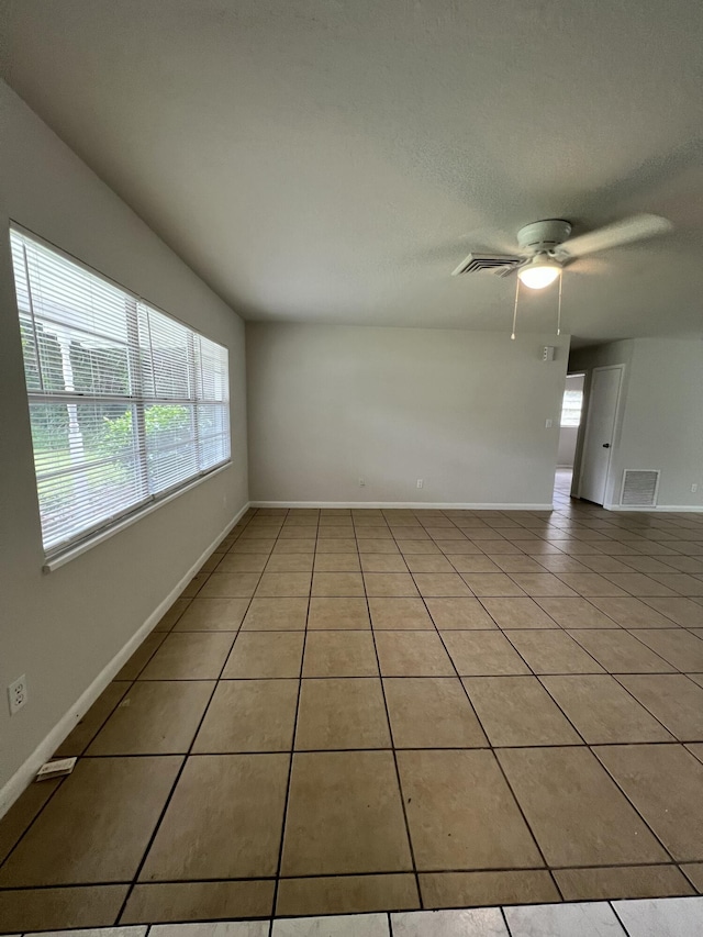 spare room with ceiling fan and light tile patterned floors