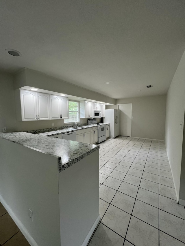 kitchen with range, white cabinets, stainless steel dishwasher, light tile patterned flooring, and kitchen peninsula