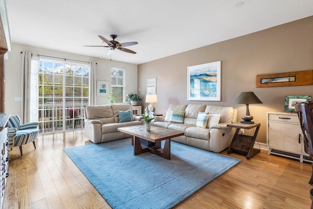 living room with light wood-type flooring, ceiling fan, and a textured ceiling