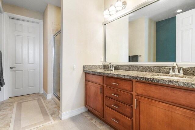 bathroom featuring a shower with shower door, tile patterned floors, and vanity