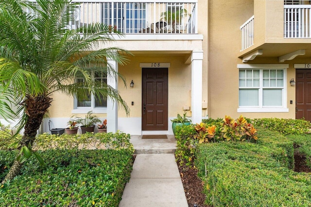 property entrance with a balcony and stucco siding